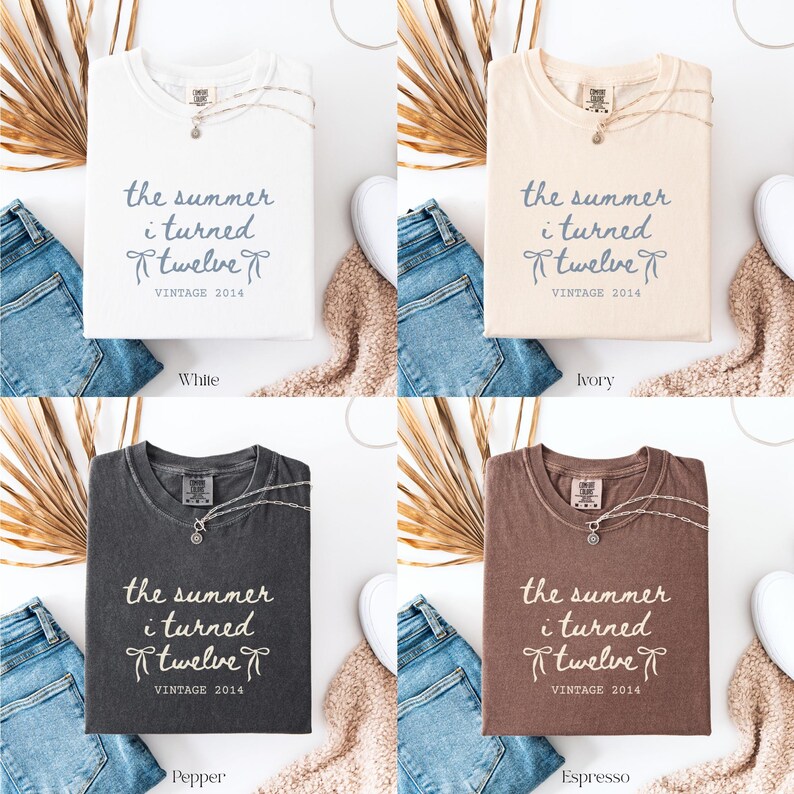 May include: Four t-shirts in white, ivory, pepper, and espresso colors, each folded and displaying the text "the summer i turned twelve VINTAGE 2014". Each shirt is paired with jeans and a necklace.