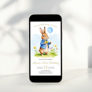 Può includere: Un invito digitale per una festa di primo compleanno con un coniglio dei cartoni animati che tiene un palloncino blu con il numero "1" sopra. Il testo dell'invito recita: "Un dolce coniglietto compie un anno. Unisciti a noi per festeggiare il primo compleanno di Mason. Sabato 15 settembre alle 13:00. Residenza Watson, 123 Rabbit Avenue, San Diego, CA. RSVP al 123-456-7890."