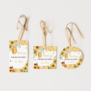 Può includere: Tre etichette di ringraziamento con un design a forma di alveare, girasoli e favo. Il testo sulle etichette recita "Grazie per essere qui! Con affetto, Olivia."