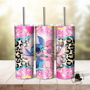 May include: Three stainless steel tumblers with pink, gold, and blue glitter designs. Each tumbler features a cartoon image of Stitch and Angel from the Disney movie Lilo & Stitch. The tumblers have a leopard print pattern and a straw.