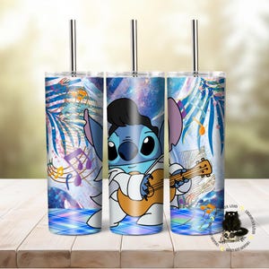 May include: Three stainless steel tumblers with a blue and white design featuring a cartoon character playing a guitar. The background includes musical notes and a galaxy pattern.