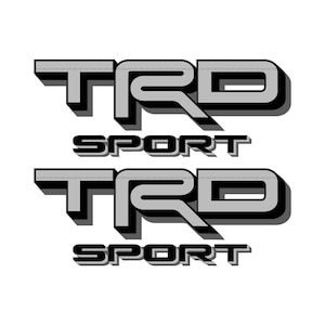May include: Two gray and black TRD Sport logos are displayed on a white background. The logos have a 3D effect, with the letters TRD stacked above the word Sport. The letters are gray with black shadows.