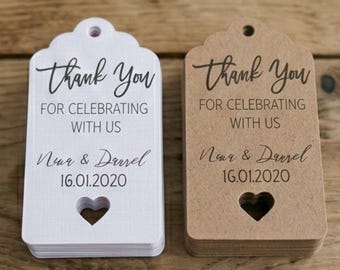May include: Two wedding favor tags, one white and one brown, with a scalloped top and a heart-shaped cutout. The tags read "Thank You" and include names and a date.