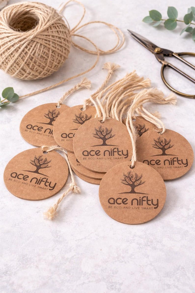 May include: A collection of round, brown paper tags with the text "ace nifty" and a tree logo, strung with natural twine. A ball of twine and scissors are also visible, suggesting a craft or eco-friendly product theme.