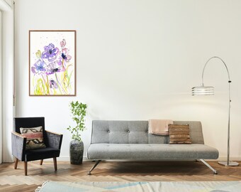 May include: A watercolor painting of purple flowers in a wooden frame hanging on a white wall above a gray sofa with a throw blanket and pillows. A potted plant sits on the floor next to a gray armchair.