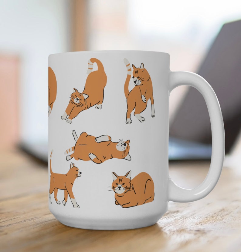 May include: White ceramic mug featuring a design of orange tabby cats in different poses. The cats are outlined in black and have white markings.