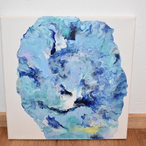 Könnte beinhalten: Ein quadratisches Leinwandgemälde mit einem abstrakten, flüssigen Acryl-Guss-Design. Die Komposition zeigt eine zentrale organische Form, die mit wirbelnden Schattierungen von Hellblau, Dunkelblau, Türkis, Weiß und blassem Gelb gefüllt ist.