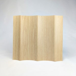 May include: A light brown wooden room divider with a wavy design. The divider is made of thin vertical panels.