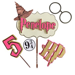 Peut inclure: Un ensemble de décorations de gâteau sur le thème d'Harry Potter. L'ensemble comprend un numéro 5 rose et or, un "Happy" rose et or avec un éclair, un topper de nom "Penelope" rose et or, un chapeau de sorcière marron, un topper rond blanc avec "9 3/4" écrit dessus et une paire de lunettes rondes noires.
