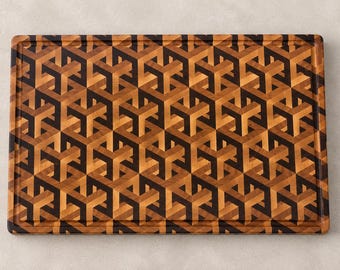 May include: A rectangular wooden cutting board featuring an intricate end-grain pattern of interlocking geometric cubes in contrasting shades of light brown, medium brown, and dark brown wood, finished with a grooved border along the edges.