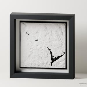 May include: A square black shadow box frame containing a white textured relief map. The map features black landmass silhouettes set against a raised, uneven white surface that mimics topographical terrain. The text Digital model preview is visible.