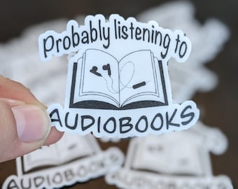 Può includere: Adesivo bianco con testo nero e un'illustrazione di un libro con cuffie. Il testo dice "Probably listening to audiobooks".