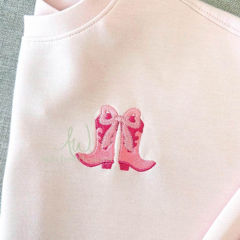 May include: Pink embroidered cowboy boots with a bow on a pink t-shirt.