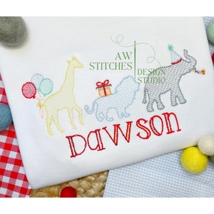 May include: A white onesie with an embroidered design of a giraffe, lion, and elephant. The animals are in a line and the elephant is wearing a party hat. The onesie also has the name "Dawson" embroidered in red.