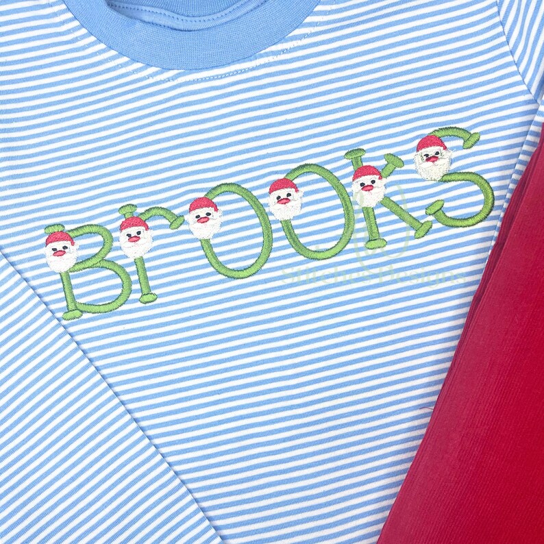 May include: A blue and white striped long-sleeve shirt with the name "BROOKS" embroidered in green with Santa Claus faces on each letter.