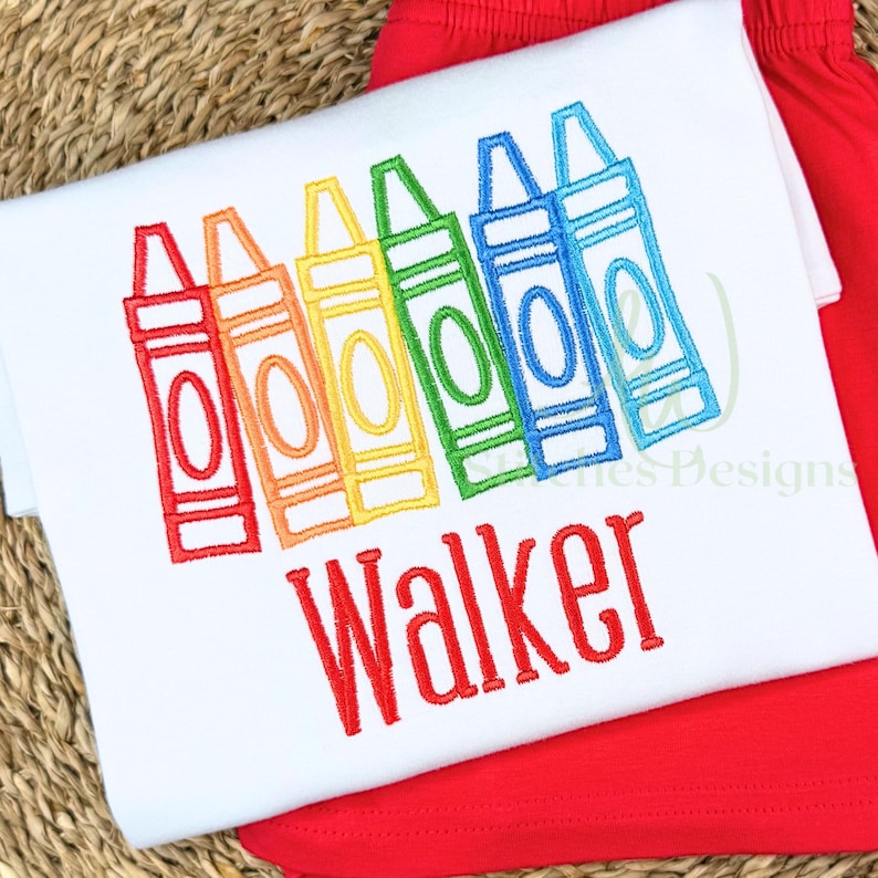 Embroidered design of colorful crayons with the name 'Walker' on a white fabric background.