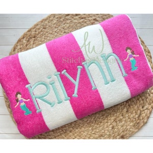 May include: Pink and white striped beach towel with the name "RiLynn" embroidered in turquoise and two mermaid figures embroidered on the towel.