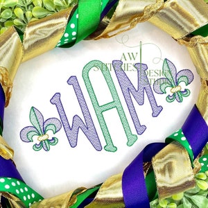 May include: Purple, green, and gold embroidered monogram "WAM" with two fleur-de-lis on either side. The monogram is on a white background.