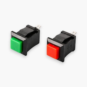 May include: Two black rectangular electrical switches with colored square buttons. One switch has a green button, and the other has a red button. The switches have silver-colored metal terminals.
