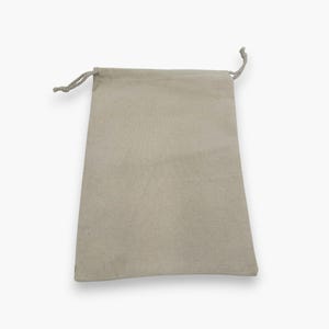 May include: A beige drawstring bag made of a soft, natural fabric. The bag has a rectangular shape with a rounded bottom and a drawstring closure at the top. The neutral color makes it suitable for various uses.