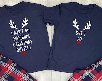 May include: Two navy blue t-shirts with a reindeer design and the text "I don't do matching Christmas outfits" and "But I do". The shirts are paired with red and blue plaid pajama pants.