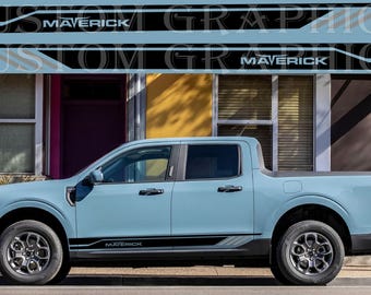 May include: A light blue Ford Maverick pickup truck with black and gray graphics on the sides. The graphics include the word "Maverick" on the doors and the tailgate.