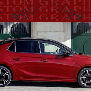 May include: A red hatchback car with black accents, including the roof and wheels, is parked in front of a building with green doors. The car has the text "CUSTOM GRAPHICS" in a repeating pattern across the top of the image.