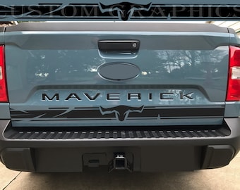 May include: A blue Ford Maverick pickup truck with a black tailgate decal featuring a bull's head and the word "Maverick".