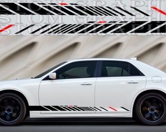 Può includere: Berlina bianca con strisce da corsa nere e rosse sui lati. Le strisce sono composte da linee diagonali e sono accentuate dal rosso. L'auto è parcheggiata su una superficie grigia.