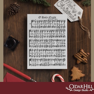 May include: A sheet of music with the lyrics and sheet music for the Christmas carol "O Holy Night". The sheet music is on a wooden table with a red envelope, a black inkwell, a candy cane, and two gingerbread cookies shaped like stars and a Christmas tree.