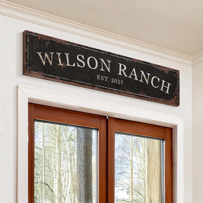 May include: A black and brown wooden sign with white text that reads "Wilson Ranch Est. 2025".