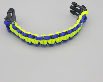 Può includere: Un braccialetto in paracord blu e giallo neon con una chiusura in plastica nera.