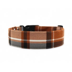 Puede incluir: Un collar de perro de cuadros marrones, negros y blancos con una hebilla de plástico negra.