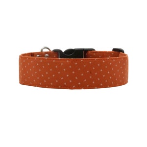 May include: Orange dog collar with a white cross pattern. The collar has a black buckle and a silver D-ring.