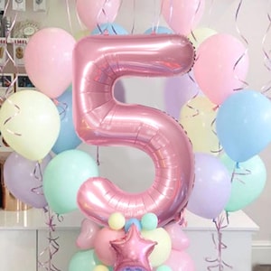 Peut inclure: Une composition festive de ballons avec un grand ballon rose en forme de chiffre 5 au centre. Autour, des ballons aux couleurs pastel rose, bleu, vert et jaune. Une étoile et des petits ballons forment la base.