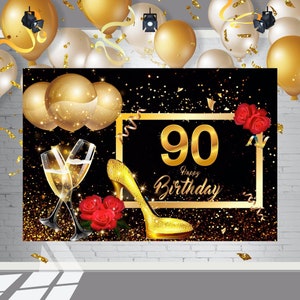 May include: A black backdrop with gold glitter and confetti. A gold frame with the number 90 and the text "Happy Birthday" in gold. Two gold champagne flutes, a gold high heel shoe, and red roses.