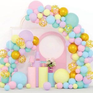 May include: Pastel coloured balloons in various sizes and shapes, including round, heart, and star, arranged in an arch. The balloons are tied together with gold string and have gold confetti inside. The balloons are against a white background.