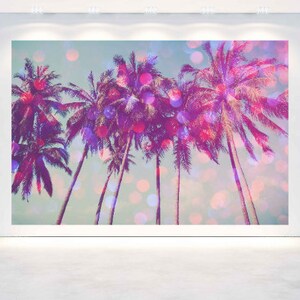 May include: A large wall art print featuring a tropical scene with several palm trees. The artwork has a vibrant color palette of pink, purple, and teal, with bokeh effects. The image is displayed on a white wall.
