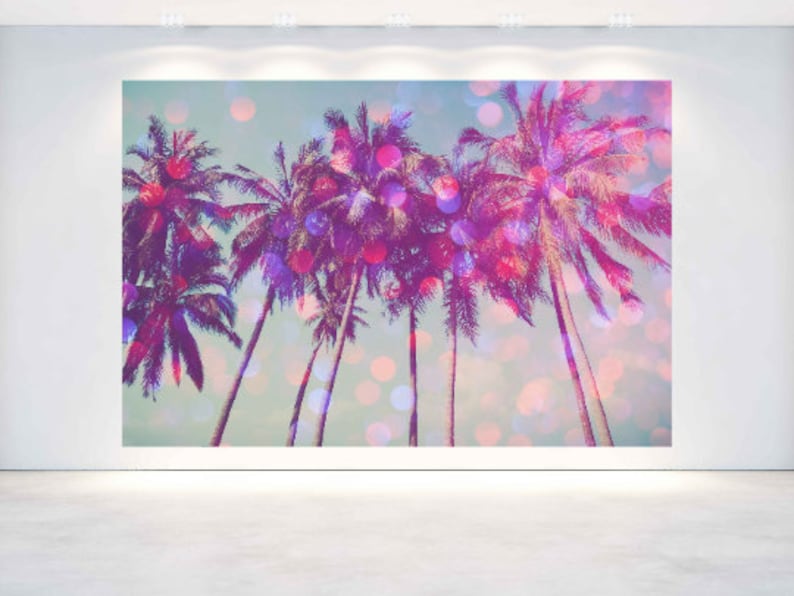 May include: A large wall art print featuring a tropical scene with several palm trees. The artwork has a vibrant color palette of pink, purple, and teal, with bokeh effects. The image is displayed on a white wall.