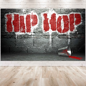 May include: Red spray paint on a brick wall with the word "HIP HOP" in large letters. A silver paint can is tipped over on the ground with red paint spilling out.