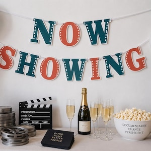 May include: A cinema-themed party display featuring a NOW SHOWING banner in teal and orange, a film projector, film reels, a clapperboard, a bottle of champagne with four flutes, a bowl of popcorn, and napkins with the text GOOD FILMS BETTER PEOPLE.