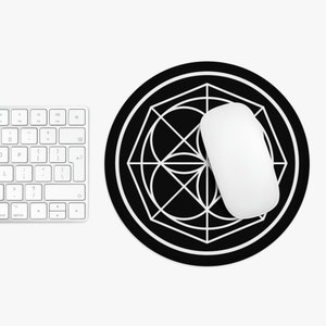 May include: A black round mouse pad with a white geometric design. A white computer mouse is on top of the mouse pad.