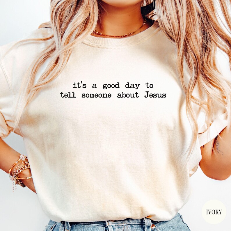 K&ouml;nnte beinhalten: Cremefarbenes Sweatshirt mit dem schwarzen Text "it's a good day to tell someone about Jesus". Das Shirt hat eine lockere Passform und ein schlichtes Design. Das Wort "IVORY" ist unten rechts aufgedruckt.