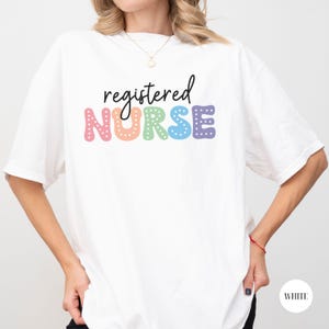 May include: White t-shirt with the text "registered NURSE" in rainbow letters with white polka dots.