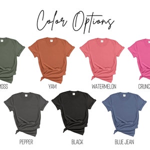Puede incluir: Siete camisetas de diferentes colores mostradas sobre un fondo blanco. Los colores son verde musgo, naranja quemado, rosa sand&iacute;a, rosa fuerte, gris antracita, negro y azul vaquero.
