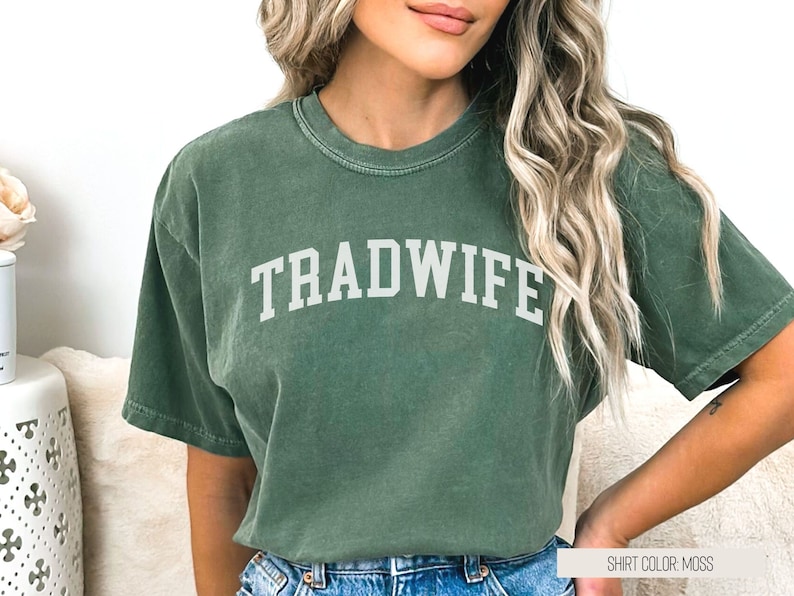 Puede incluir: Una camiseta verde con el texto "TRADWIFE" en letras blancas. El color de la camiseta es musgo.