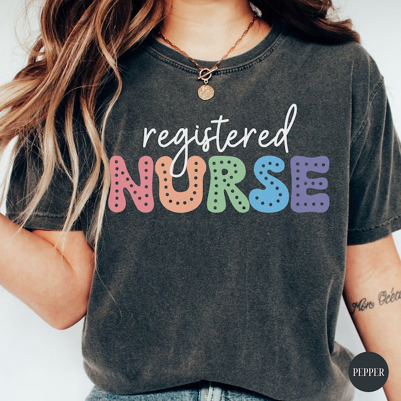 May include: A dark gray t-shirt with the text "registered NURSE" in colorful, dotted letters. The letters are in a rainbow color scheme.