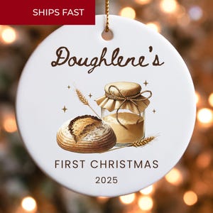 May include: White ceramic Christmas ornament with a watercolor illustration of bread, a jar of flour, and wheat. The text reads "Doughlene's First Christmas 2025." A red banner at the top says "SHIPS FAST."