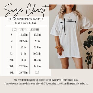 Op de afbeelding: Wit Gildan Comfort Colors unisex T-shirt voor volwassenen. De afbeelding bevat een maattabel met afmetingen in inches voor maten S tot 4XL. Het model draagt maat XL. De tabel toont breedte- en lengtematen.