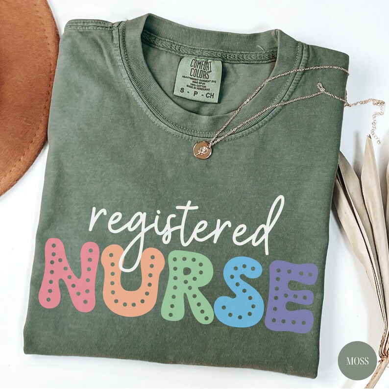 May include: A green t-shirt with the text "registered NURSE" in white and colorful letters with polka dots. The letters are in a rainbow color scheme.